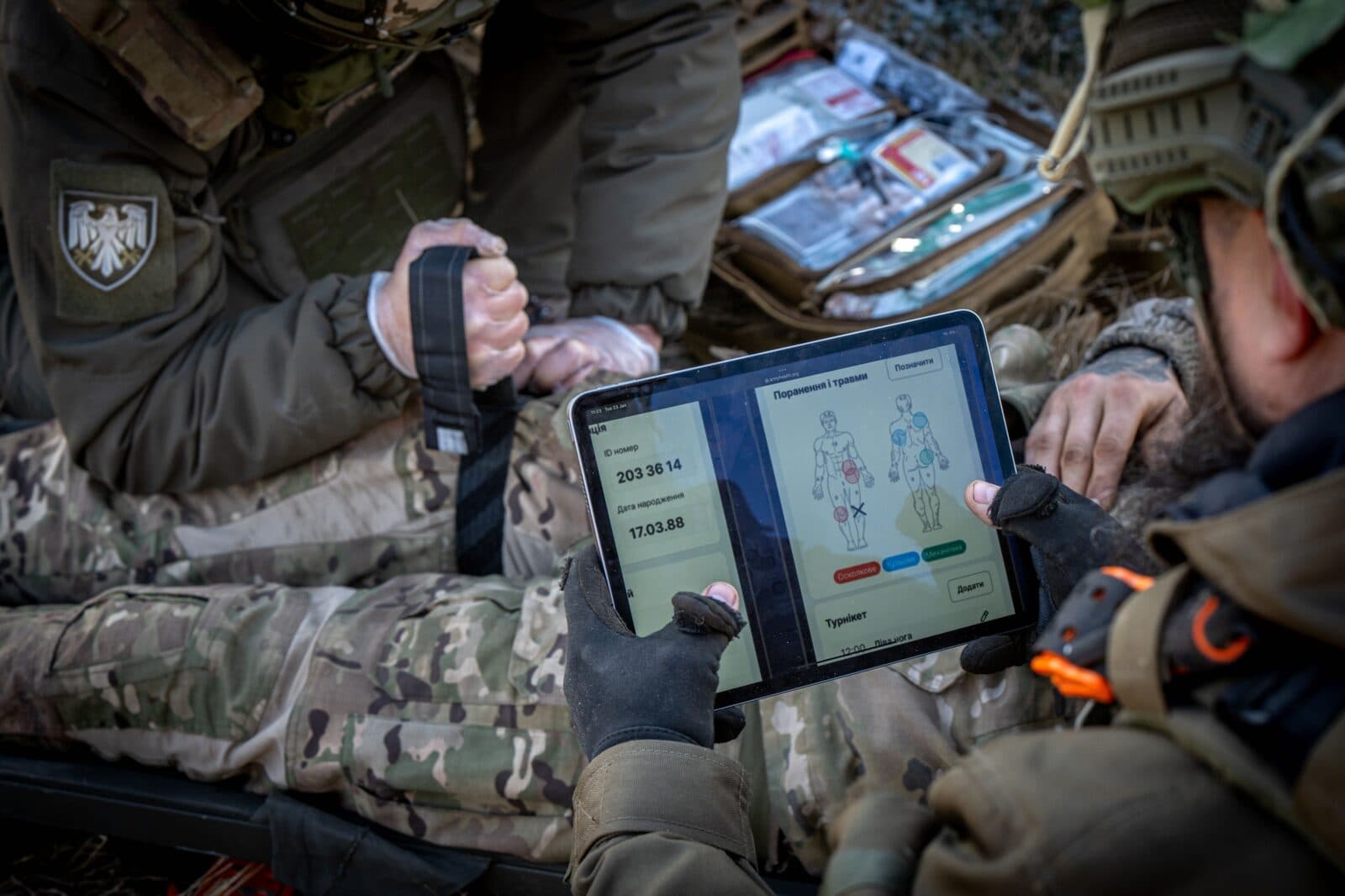 Військовий медик з планшетом ArmyHealth під час польової роботи з пораненим